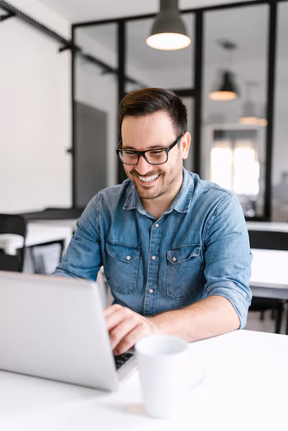 smiling-young-man-using-laptop-modern-office_109710-4878